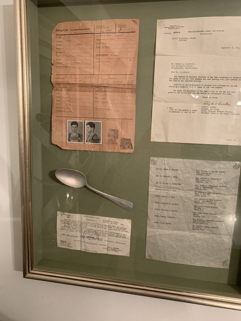 Glass shadowbox containing an aluminum spoon my dad ate with while being held by the Nazis, his POW camp records, a list of his crew, and letters from the War Department.